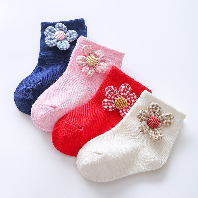 Flower-embellished crew socks in navy, pink, red, and white, each with fabric flower